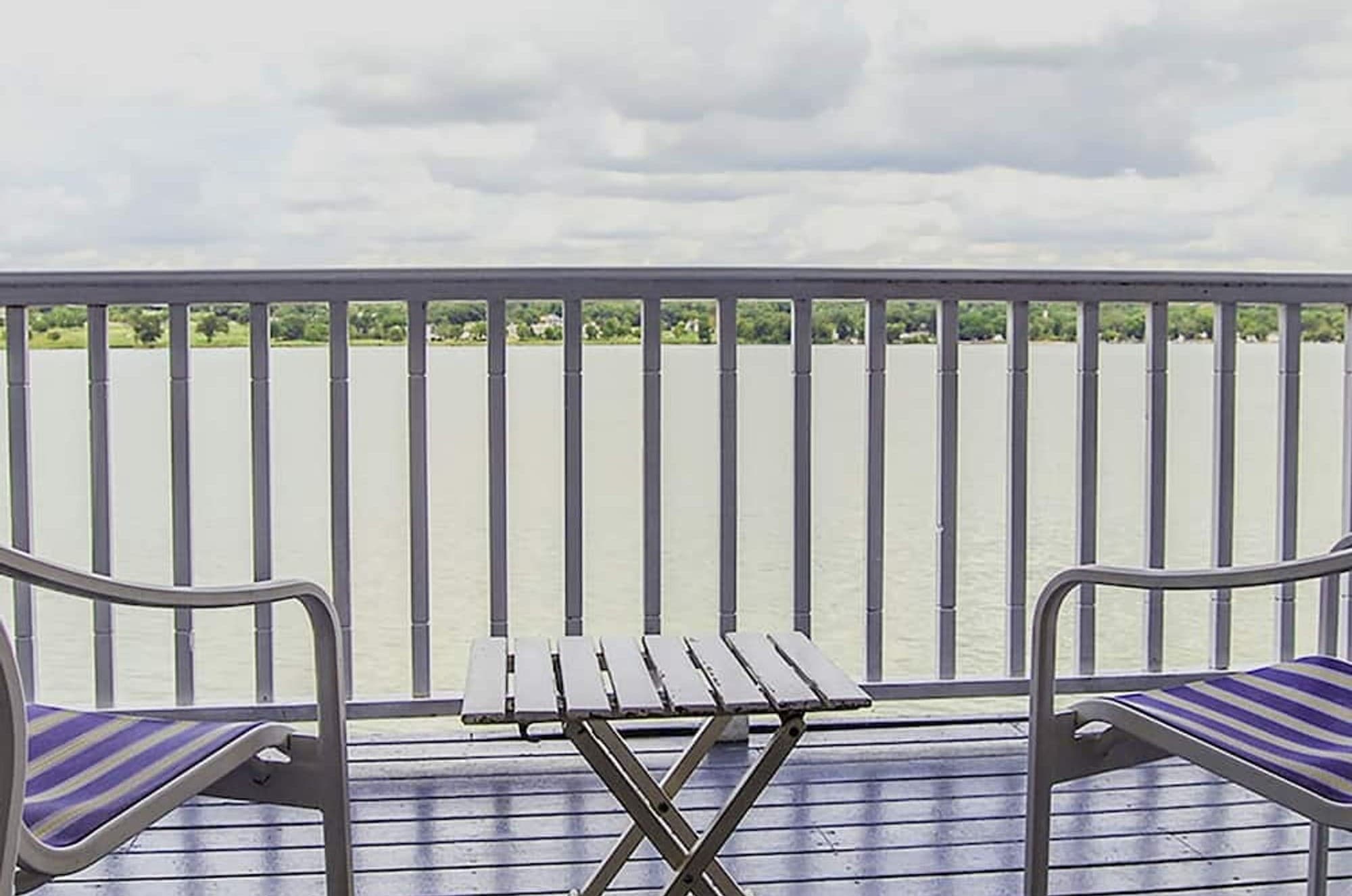 Two striped chairs and a small table on a private deck over the water