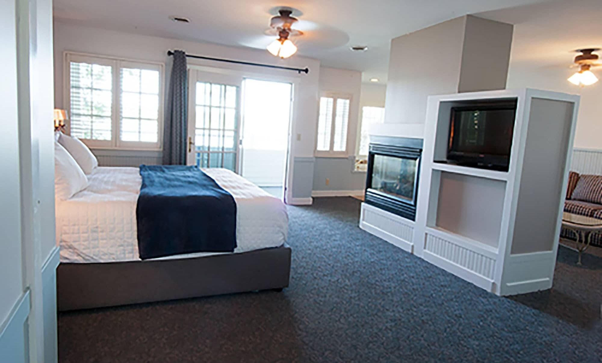 A king room with a navy throw, a gas fireplace, and French doors to the porch