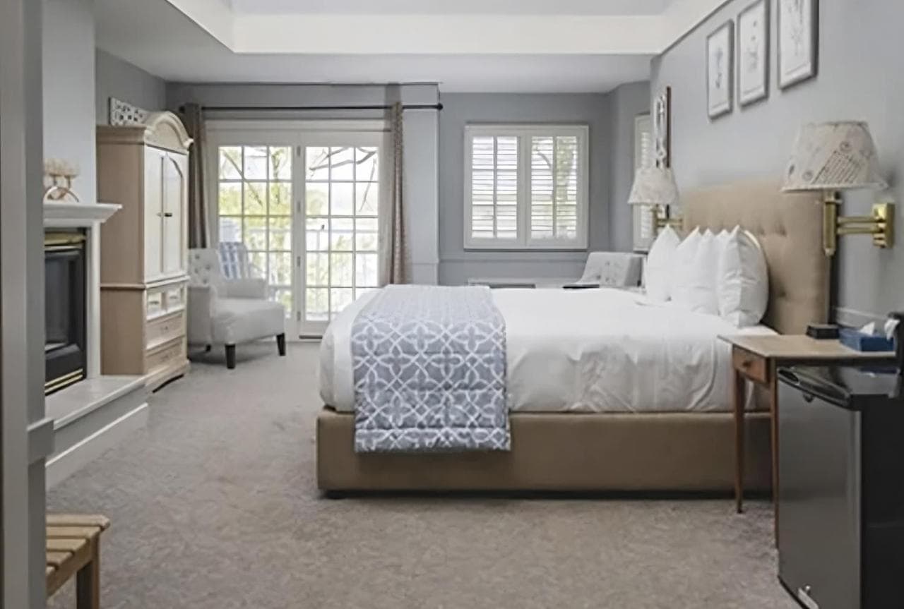 A king bed with a patterned runner, an armchair, and windows toward the lake