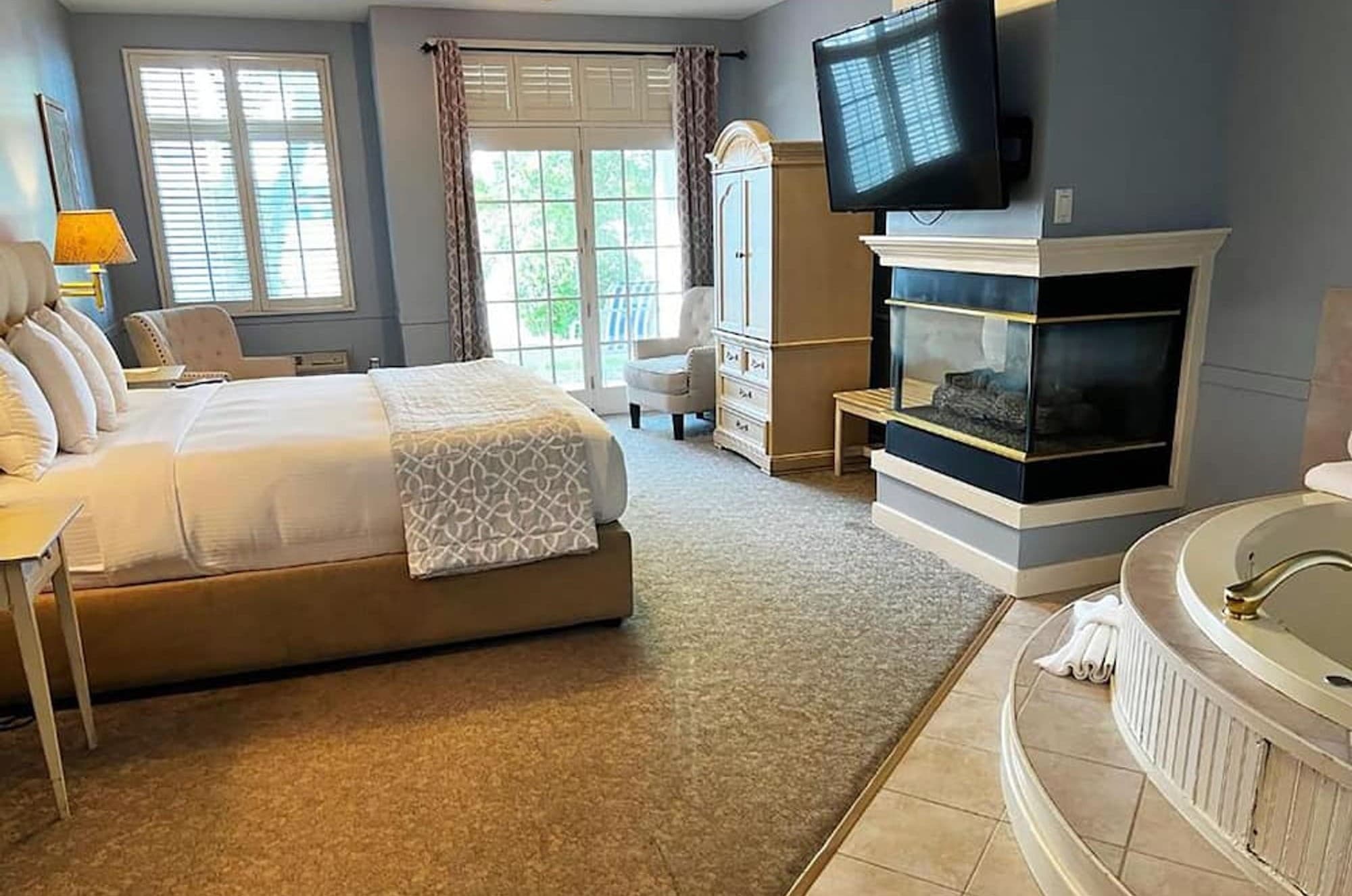 A king bed beside a corner gas fireplace and a two-person whirlpool