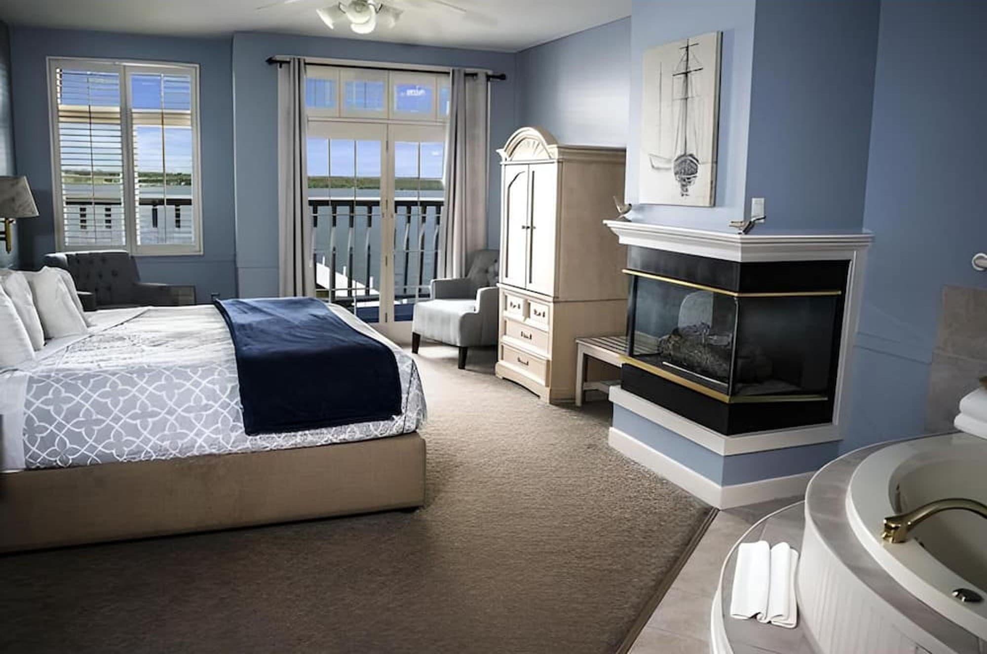 A King Lake View room with a navy throw, a corner fireplace, and a whirlpool by the window