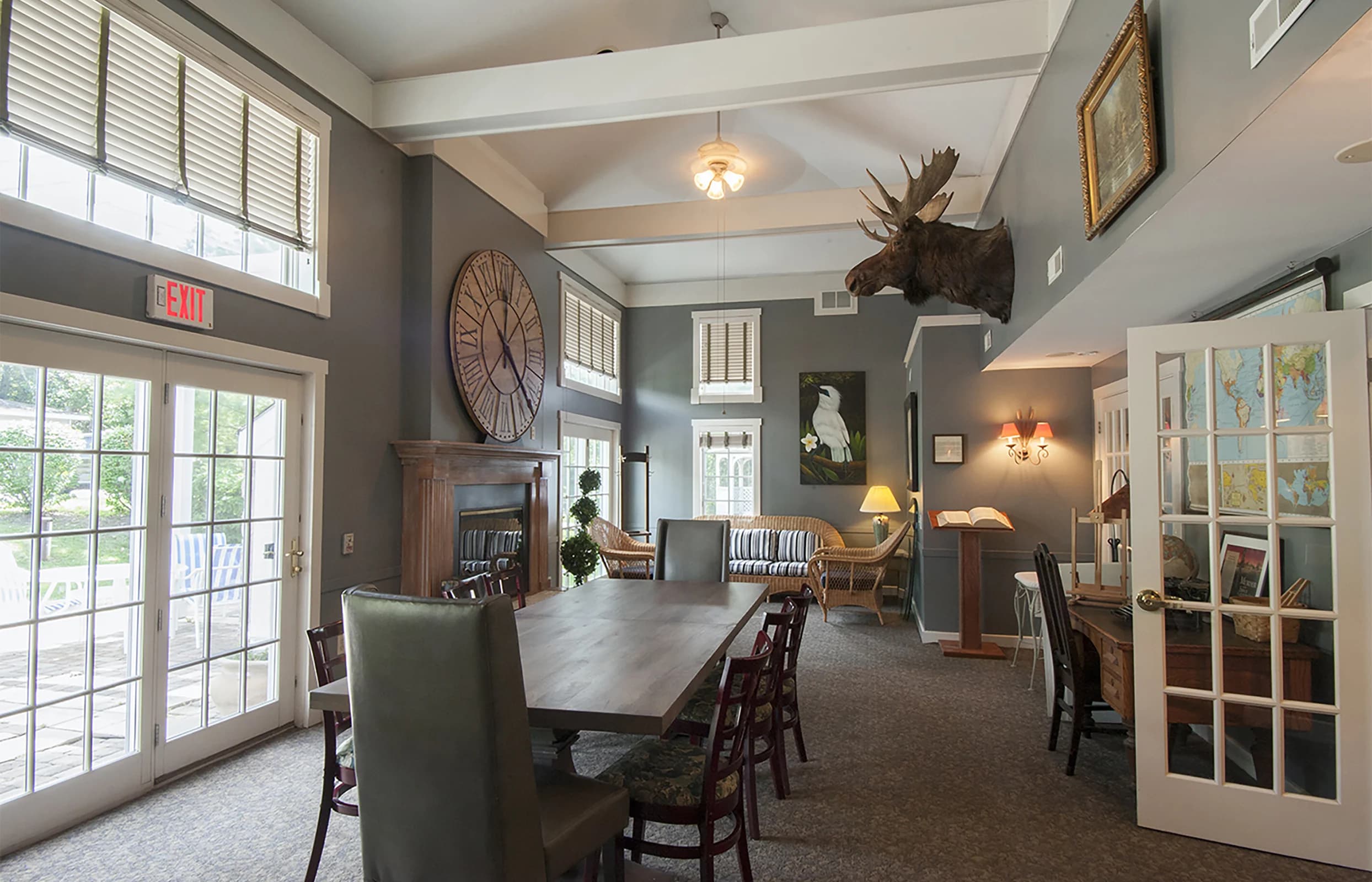 The gathering room, with a long table, French doors, and a moose mount on the wall