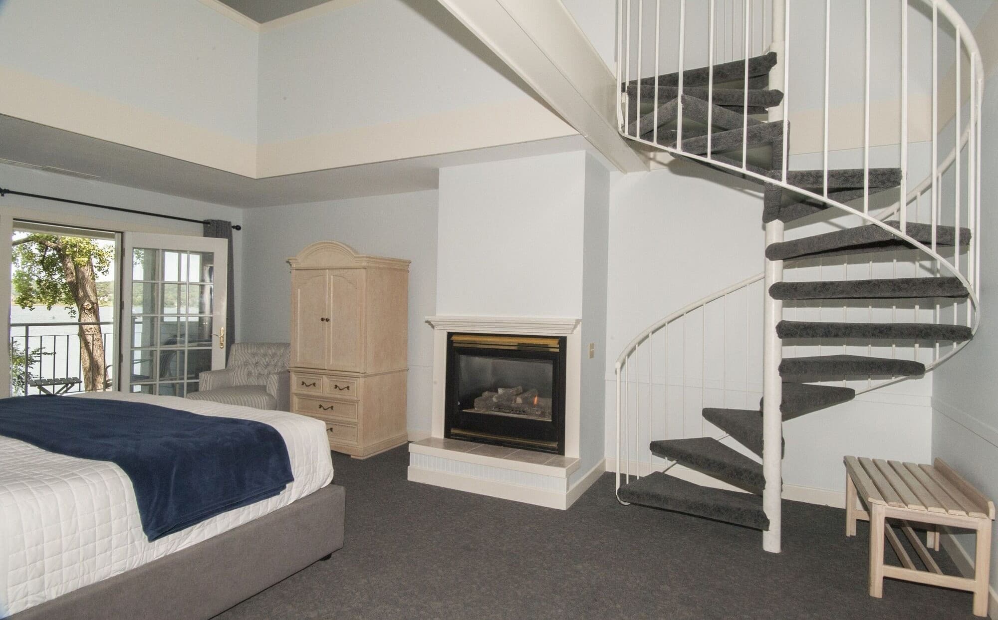 A King Loft room with a gas fireplace and a white spiral stair up to the loft